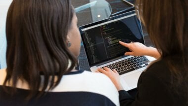 Two people reviewing data on a laptop screen.